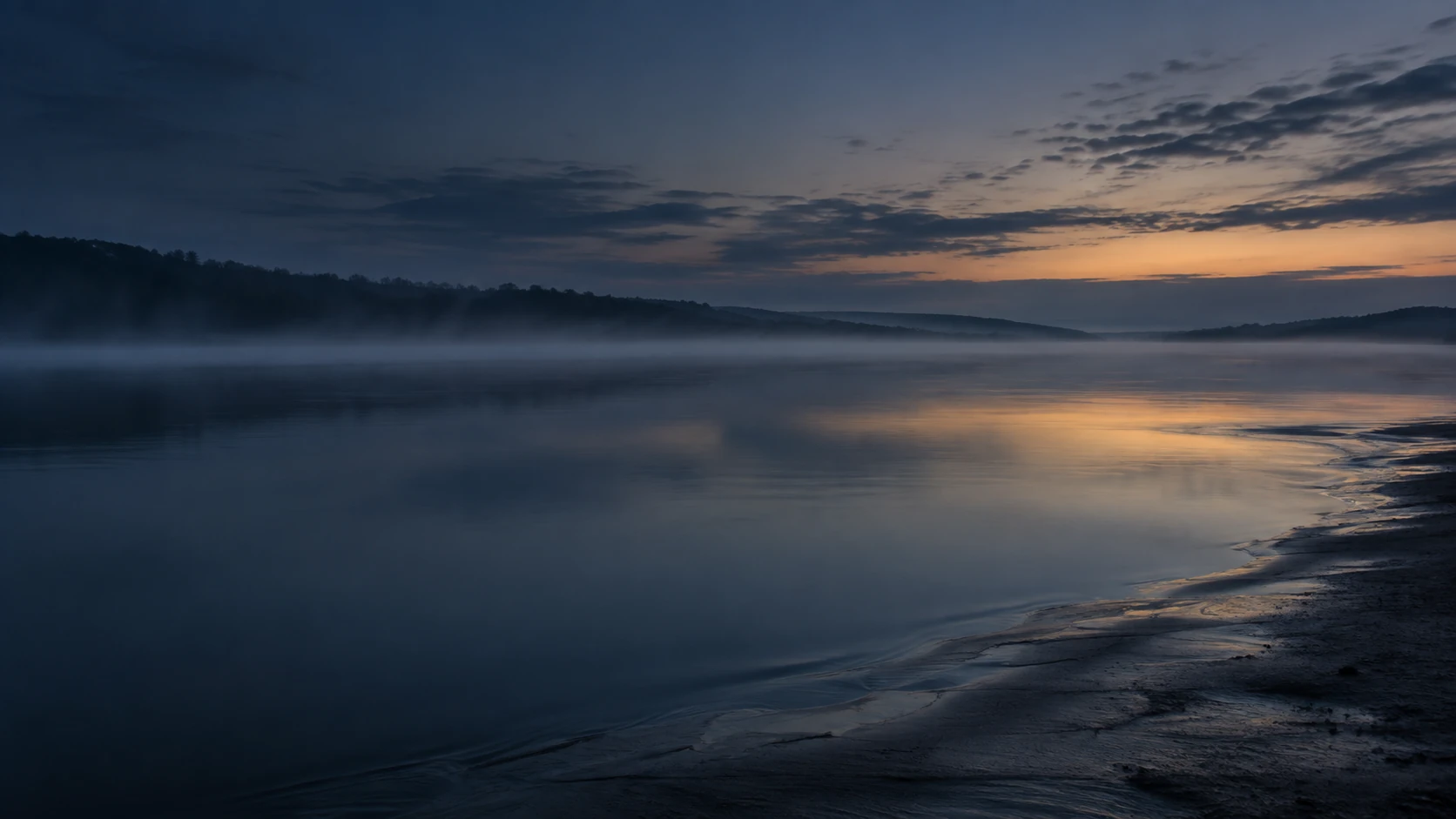 Quiet water and an empty shoreline settling into blue hour